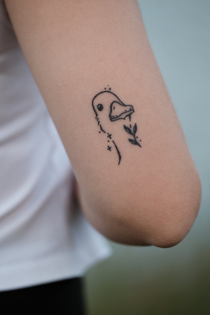 Close-up of a delicate duck tattoo on a woman's arm, showcasing simplicity.
